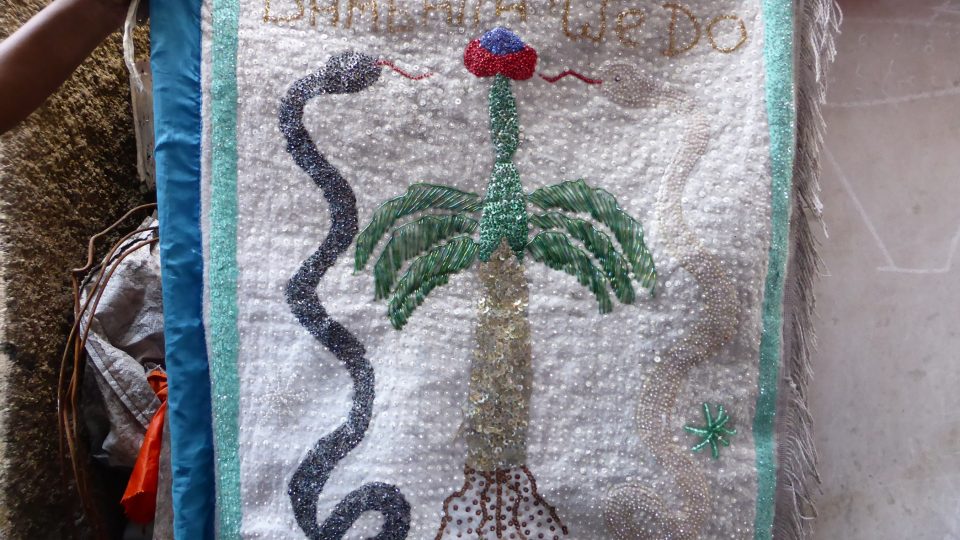 Drapo, obřadní prapor vyšitý z flitrů. Dnes jsou drapa vysoce ceněna jako tradiční haitské naivní umění a prodávají se za tisíce dolarů