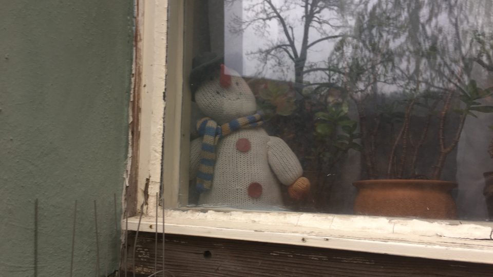 Osamělý sněhulák za oknem v jedné z úzkých uliček na Malé Straně, kudy dnes nikdo nechodí