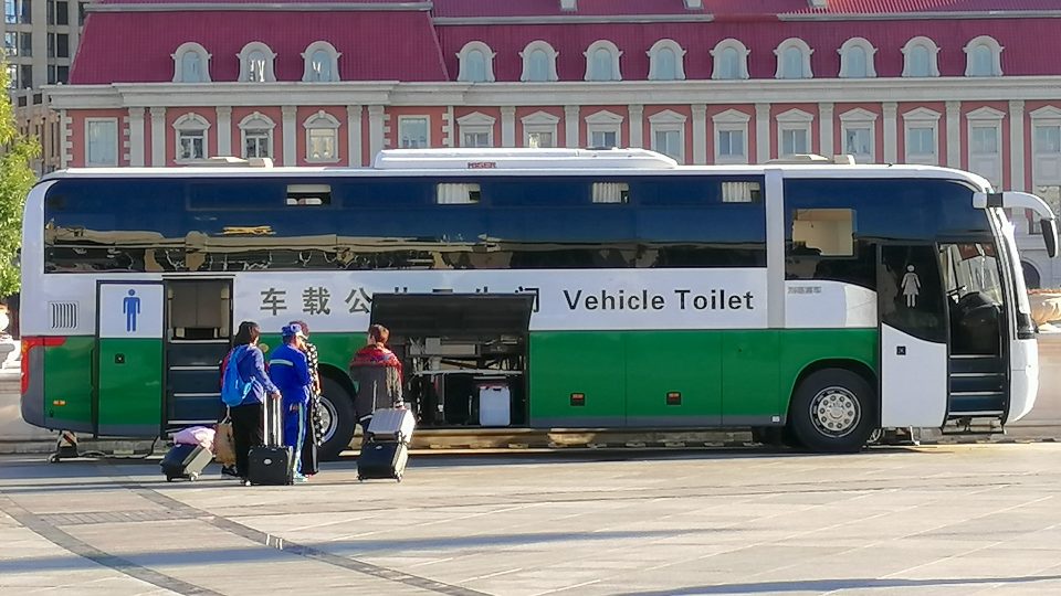 Veřejné záchody vestavěné do autobusu před Hlavním tchien-ťinským nádražím s výhledem na francouzskou čtvrť s červenými mansardovými střechami